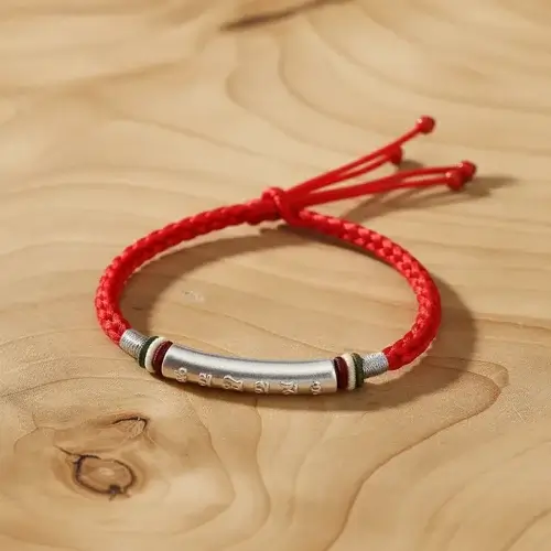 Handmade red cord buddhist mantra bracelet natural wood background detail