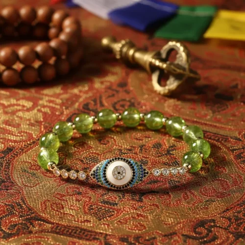 Peridot evil eye bracelet on tibetan silk with buddhist symbols