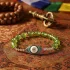 Peridot evil eye bracelet on tibetan silk with buddhist symbols