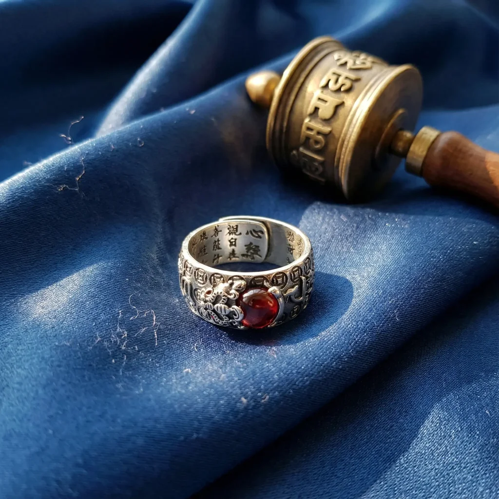 Tibetan buddhist garnet pixiu ring with prayer wheel on blue silk altar cloth