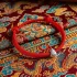 Red string Fu lucky bracelet with sterling silver charm displayed on authentic Tibetan Buddhist fabric with colorful patterns