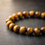 Close-up of a tiger eye bracelet with golden-brown chatoyancy on a dark textured surface
