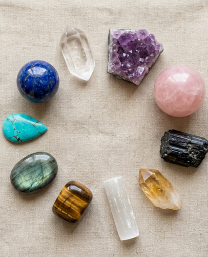 Flat lay of 10 best healing crystals for beginners including clear quartz, amethyst, rose quartz, black tourmaline, and turquoise on natural linen
