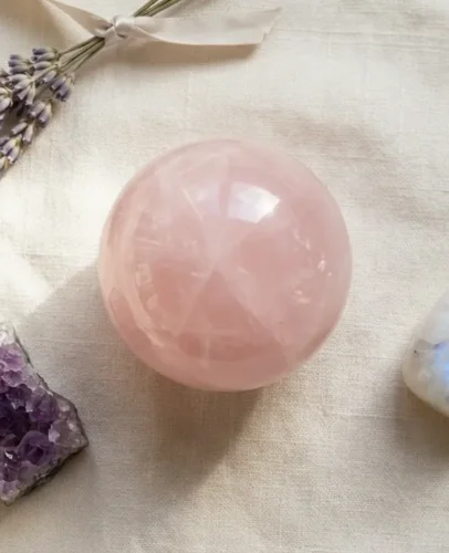 Baby Shower Crystal Gifts Rose Quartz and Amethyst A curated baby shower crystal gift set featuring rose quartz sphere, amethyst cluster, and moonstone on soft cream linen with a sprig of dried lavender