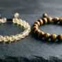 Citrine vs Tiger Eye Bracelet Comparison Side-by-side comparison of a yellow citrine bracelet and a golden tiger eye bracelet on a dark stone surface