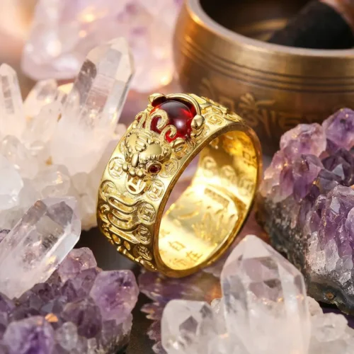 24K gold plated PiXiu red garnet wealth ring resting among clear quartz crystals and amethyst clusters with a Tibetan singing bowl in the background