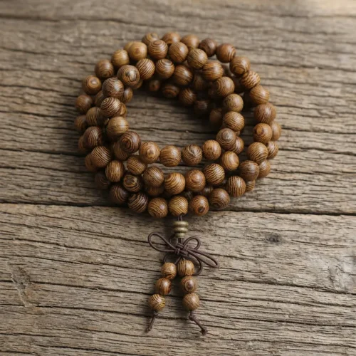 108 wenge wood mala beads bracelet with tiger-stripe grain pattern and traditional Chinese knot tassel on rustic wooden surface