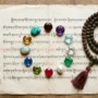 What Your Birthstone Says About You A flat lay arrangement of 12 gemstones representing each birth month, including garnet, amethyst, aquamarine, diamond, emerald, pearl, ruby, peridot, sapphire, opal, topaz, and turquoise, placed on aged Tibetan manuscript paper with soft natural light