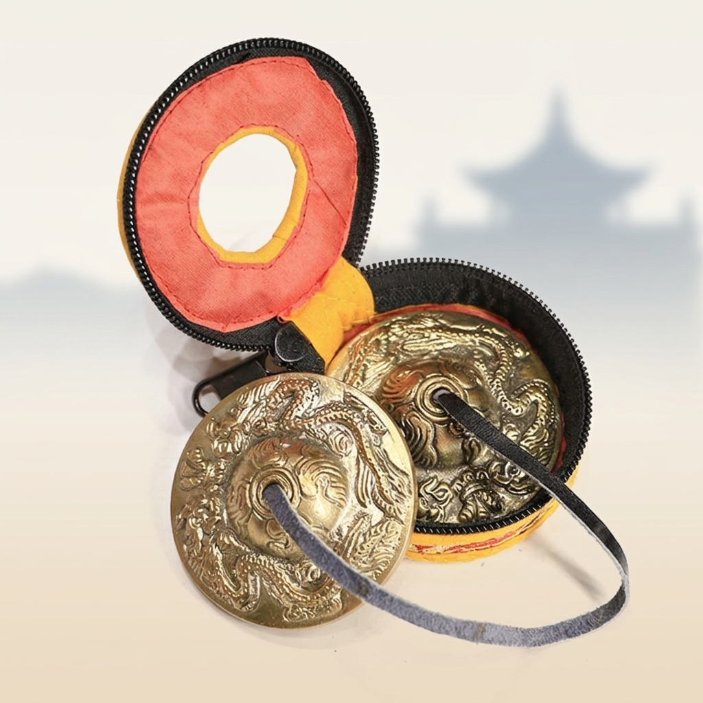 tibetan-dragon-tingsha-bells-copper-with-yellow-carry-bag-pagoda Tibetan copper tingsha bells with deep dragon relief engraving shown alongside open yellow and red zipper carry bag, pagoda silhouette in soft background