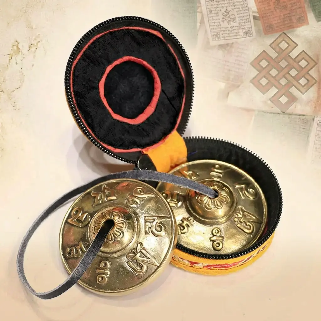 tibetan-tingsha-bells-six-true-words-mantra-black-carry-bag-endless-knot Tibetan copper tingsha bells engraved with Six True Words mantra displayed with black and red fabric carry bag, Tibetan endless knot and prayer flags background