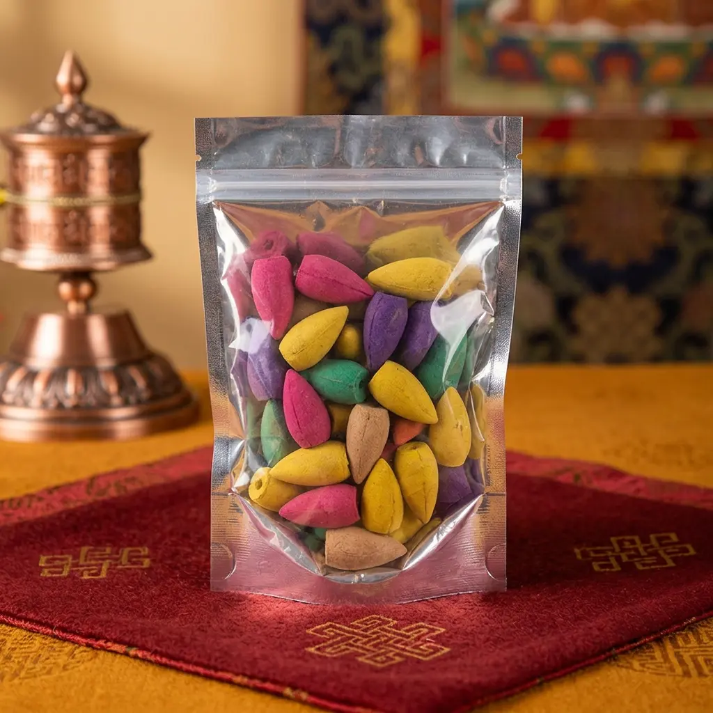Colorful Incense Cones in Transparent Pouch - Tibetan Decor Setting Clear resealable pouch filled with multicolored teardrop incense cones on red and gold Tibetan prayer mat with copper prayer wheel in background