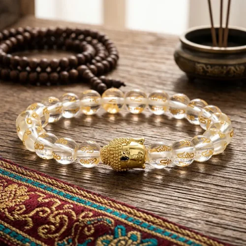 Gold Buddha mantra bracelet with translucent crystal beads and gold Om Mani Padme Hum engraving, displayed alongside a traditional 108-bead wooden mala and Tibetan incense bowl