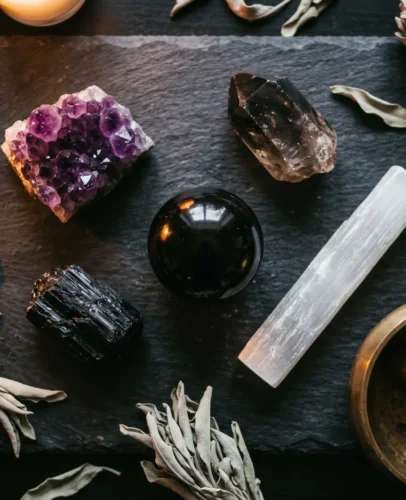 A flat-lay collection of top protection crystals including black tourmaline, obsidian, amethyst and selenite arranged on a dark stone surface