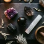 A flat-lay collection of top protection crystals including black tourmaline, obsidian, amethyst and selenite arranged on a dark stone surface