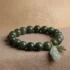 Feng Shui green jade Pixiu wealth bracelet resting on a beige textured fabric with a faint spiritual mandala design in the background