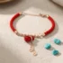 Red rope feng shui money bag bracelet with rose gold Chinese coin dangles, styled with turquoise stones — PotalaStore Tibetan wealth jewelry