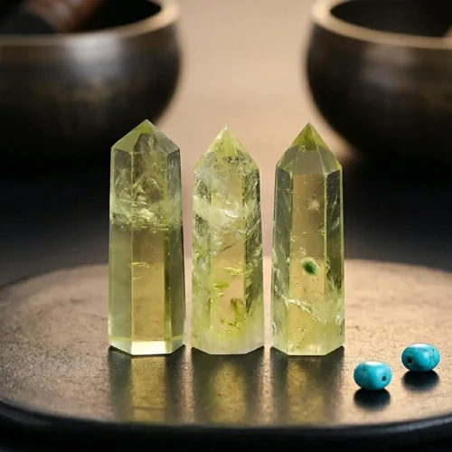 Three pale lemon-yellow natural citrine crystal towers displayed on dark surface flanked by Tibetan singing bowls and turquoise beads, showcasing natural feather inclusions and genuine unheated color
