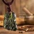 Large raw moldavite healing pendant on dark red macrame cord hanging with Tibetan wooden mala beads in the background