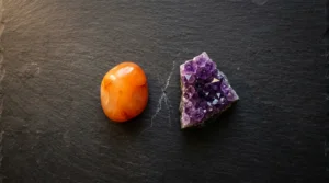 Carnelian and amethyst crystals placed side by side on a dark stone surface, illustrating crystals that should not be placed together