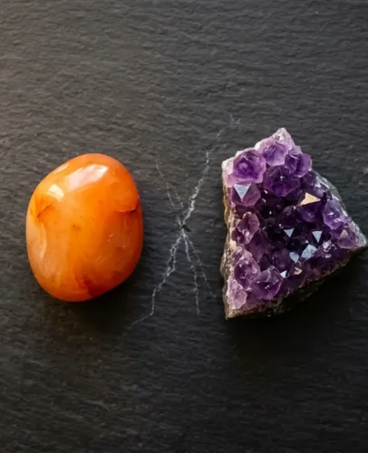 Conflicting Crystals Side by Side — Carnelian and Amethyst Carnelian and amethyst crystals placed side by side on a dark stone surface, illustrating crystals that should not be placed together