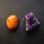 Conflicting Crystals Side by Side — Carnelian and Amethyst Carnelian and amethyst crystals placed side by side on a dark stone surface, illustrating crystals that should not be placed together