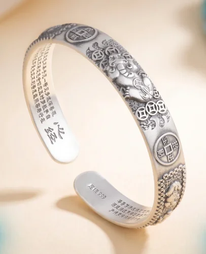 Close-up of Fortune Pixiu Lucky Bangle showing the Heart Sutra engraved on the inner band and the 足银999 fine silver hallmark stamp, with turquoise stones in background