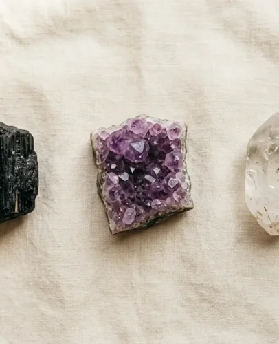 Three beginner crystals laid out on linen: clear quartz, purple amethyst, and black tourmaline