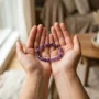 crystal-bracelet-cleansing-hands Person holding an amethyst crystal bracelet in open palms, preparing to cleanse it Nanobanana prompt: