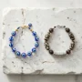 evil-eye-vs-tibetan-protection-jewelry-comparison A Turkish nazar evil eye bracelet and a Tibetan dzi bead mantra bracelet placed side by side on a natural stone surface, representing two ancient spiritual protection traditions