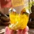 Hand holding a natural citrine wealth crystal cluster in front of Tibetan prayer flags, singing bowl, and Buddha statue — monastery-blessed by PotalaStore
