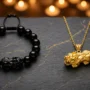 pixiu-bracelet-vs-pendant-comparison-feng-shui A black obsidian Pixiu bracelet and a gold Pixiu pendant placed side by side on dark stone, representing two forms of feng shui wealth talisman
