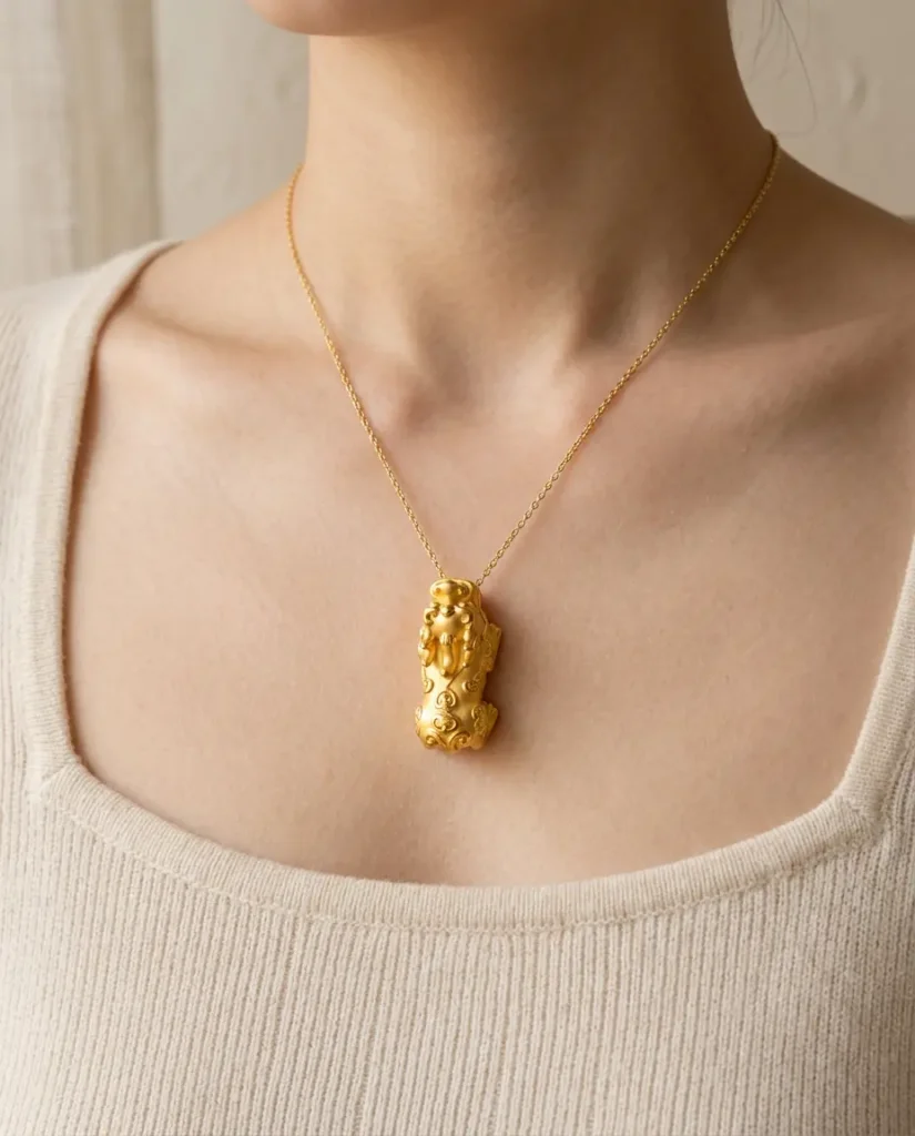 A 24K gold Pixiu pendant hanging on a fine chain against a woman's chest, with the Pixiu head pointing upward toward the face to receive heaven's blessing according to feng shui tradition