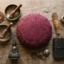 tibetan-meditation-starter-kit-components Seven authentic Tibetan meditation starter kit components laid out on a natural wood surface — zafu cushion, 108-bead mala, hand-hammered singing bowl, Tibetan incense, tingsha bells, Buddha statue, and leather journal