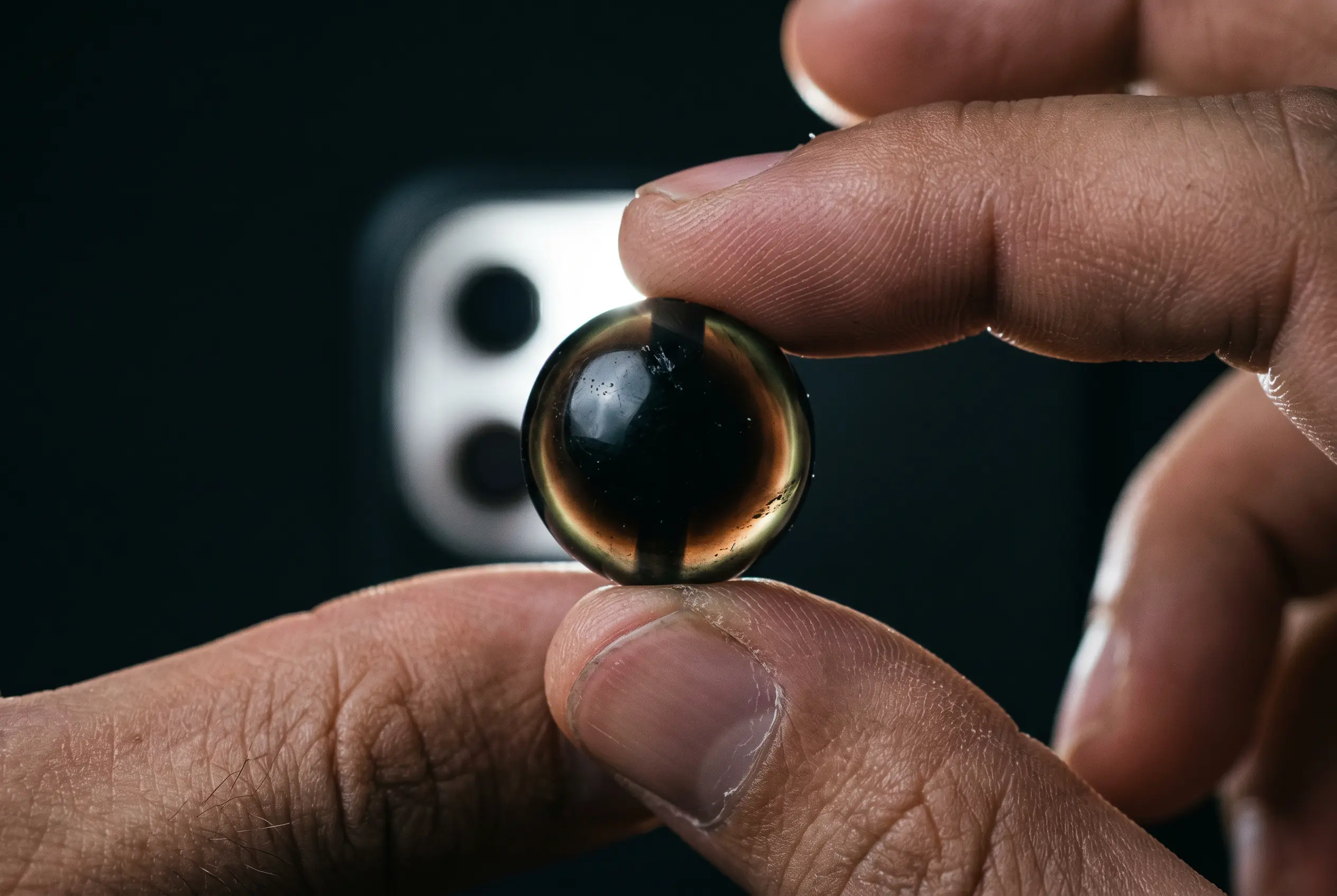 Flashlight shining through a real black obsidian bead showing a smoky tea-brown glow