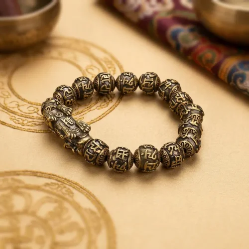 Copper Om Mani Padme Hum Pixiu bracelet on a gold mandala beside a Tibetan singing bowl