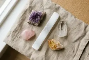 Beginner crystal collection with amethyst, rose quartz, and selenite on a wooden tray showing common crystal care mistakes