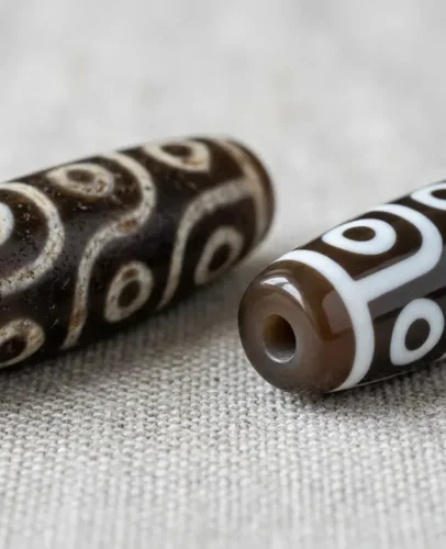 real-vs-fake-dzi-beads-comparison Real agate dzi bead next to a fake resin dzi bead, showing differences in etching depth and surface texture