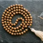 108-sandalwood-mala-beads-guru-bead-tassel Flat lay of meaningful crystal and mala bead gifts for Christmas 2026, including rose quartz, amethyst, and a sandalwood mala