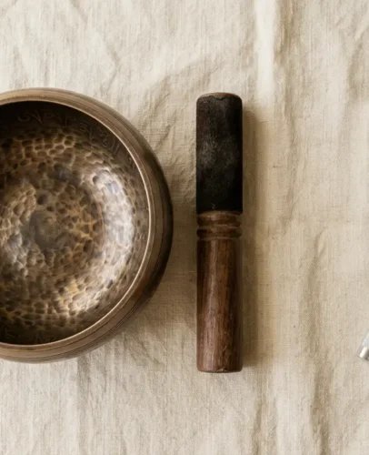 Singing bowl and tuning fork side by side for sound healing A Tibetan bronze singing bowl beside a metal healing tuning fork on a neutral surface, showing the two main sound healing tools compared