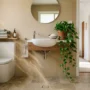 feng-shui-bathroom-stop-wealth-draining Feng shui bathroom with closed toilet lid, green plants, and earth-tone towels to stop wealth from draining