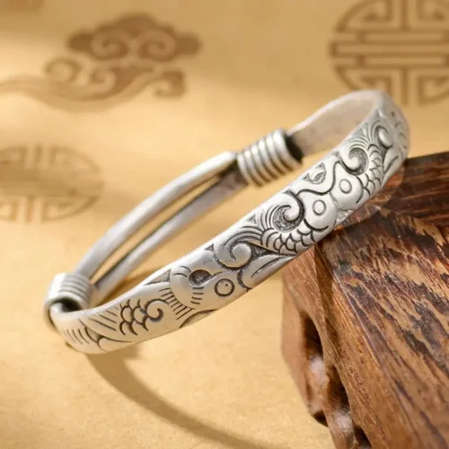Adjustable Tibetan embossed silver bracelet with a lucky fish and cloud scrollwork motif for good fortune