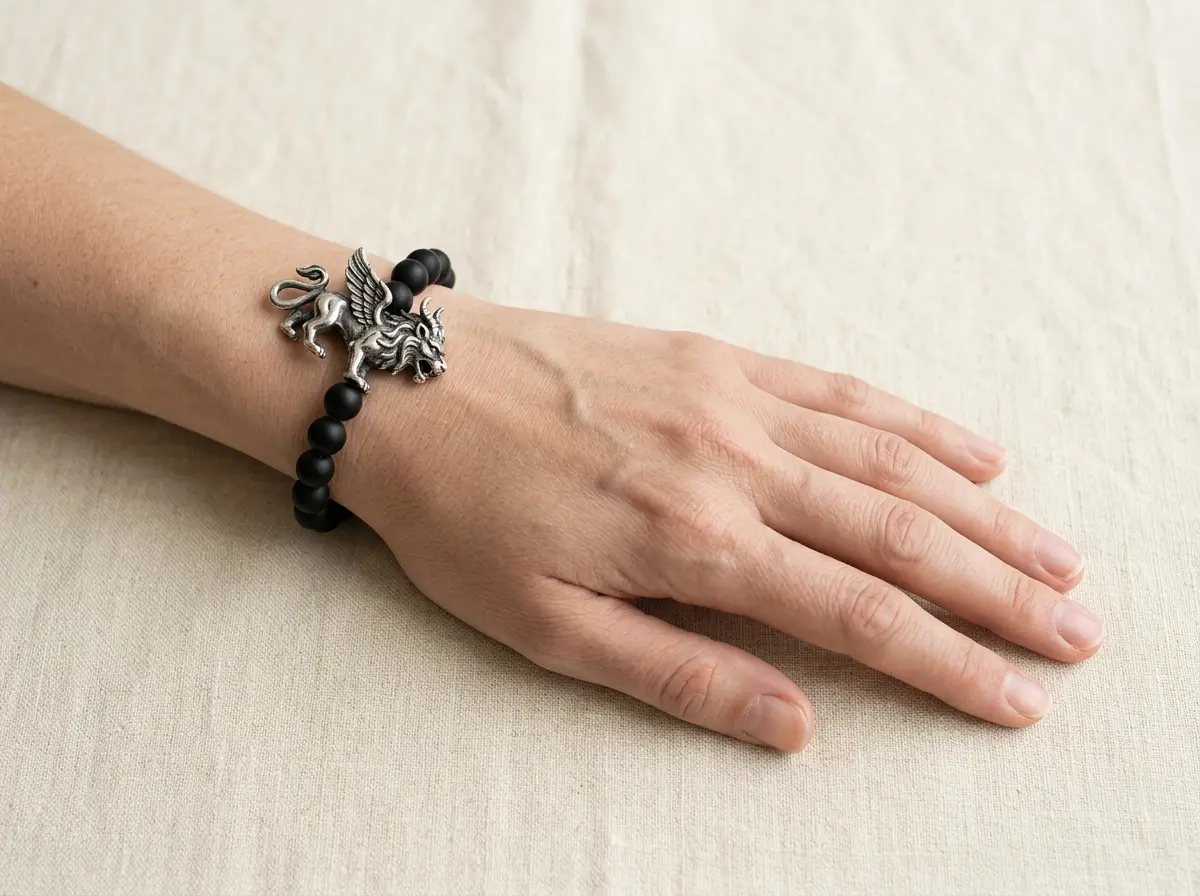Left wrist wearing a black obsidian Pixiu bracelet with the charm head facing outward toward the little finger