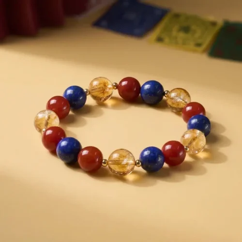 Náramek z korálků lapis lazuli, červeného achátu a citrínu, položený naplocho v kruhu na teplém béžovém pozadí s tibetskými modlitebními vlaječkami