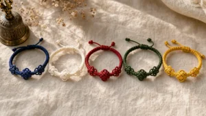 Five handwoven Tibetan braided bracelets in blue, white, red, green, and yellow arranged on natural linen