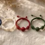 Five handwoven Tibetan braided bracelets in blue, white, red, green, and yellow arranged on natural linen