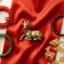 fire-goat-2027-lucky-colors-numbers-stones-hero Golden goat figurine with red and gold silk, garnet and jade bracelets for the Fire Goat 2027 lucky colors, numbers and stones