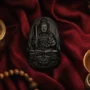 Přívěsek z černého obsidiánu Strážného Buddhy (Ben Ming Fo) na tmavém hedvábném oltáři s kadidlem, představující duchovní ochranu podle čínského zvěrokruhu.