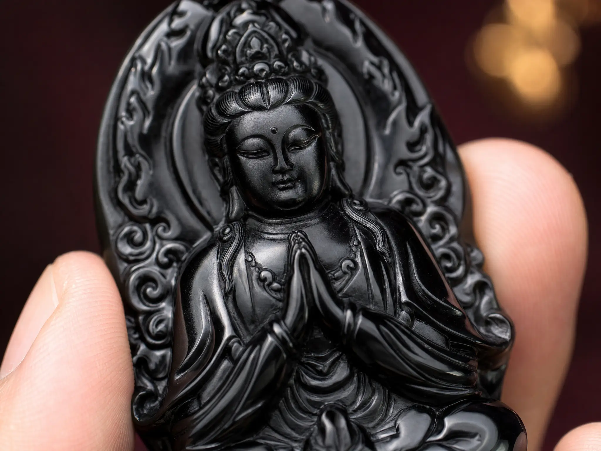 Gros plan macro d'un pendentif Bouddha Gardien en obsidienne noire sculpté à la main, révélant une iconographie détaillée du bodhisattva et un savoir-faire exceptionnel.