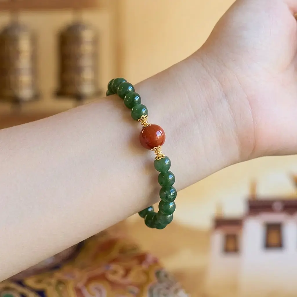 hetian-jade-red-agate-bracelet-worn-wrist.jpg Green Hetian nephrite jade and Southern Red agate bracelet on a wrist, Tibetan prayer wheels and white monastery behind