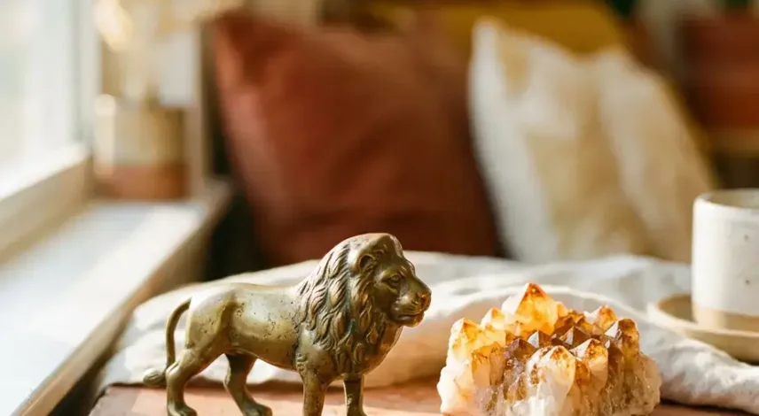 leo-season-2026-hero Golden lion figurine beside a glowing citrine crystal cluster in warm sunset light, symbolizing Leo season 2026